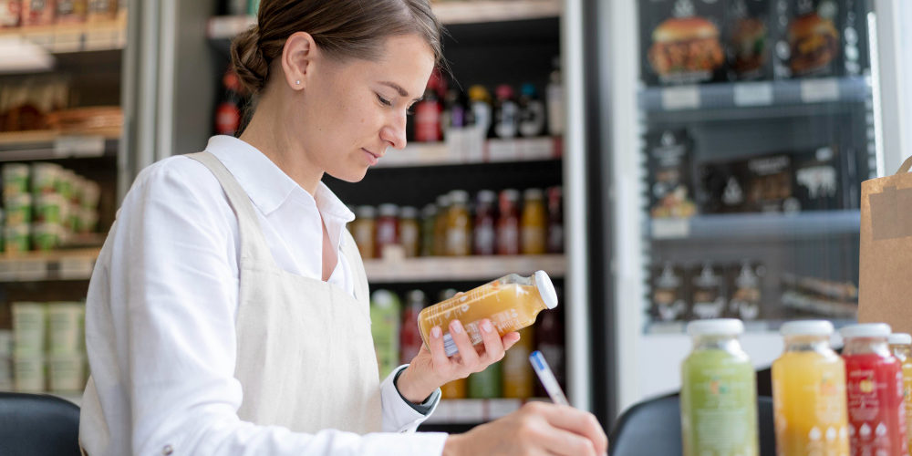 Szef kuchni lub kucharz odkładający warzywa lub produkty spożywcze do pojemników GN lub specjalnego regału, z widocznymi etykietamidatami.