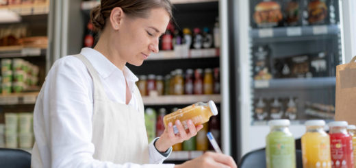 Szef kuchni lub kucharz odkładający warzywa lub produkty spożywcze do pojemników GN lub specjalnego regału, z widocznymi etykietamidatami.